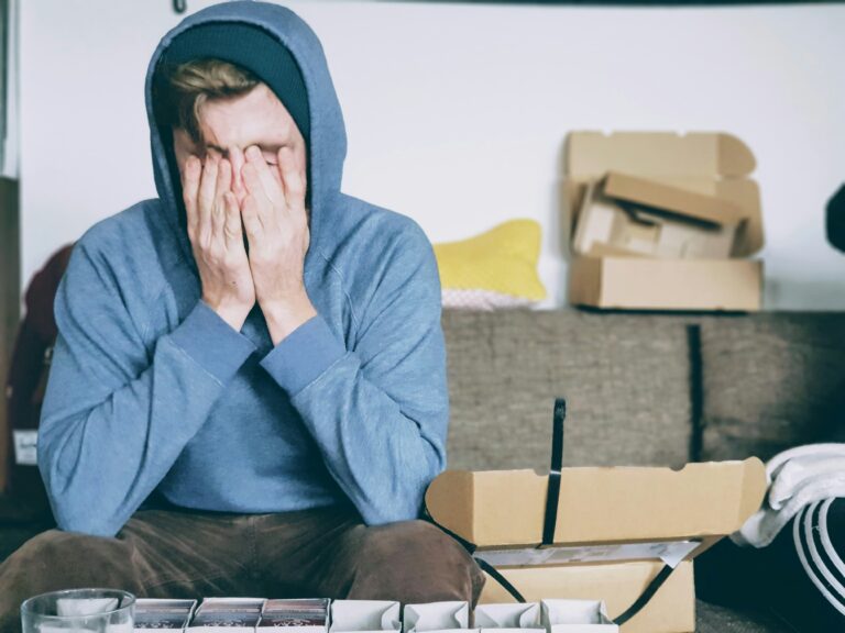 A young person sits among boxes, visibly stressed.